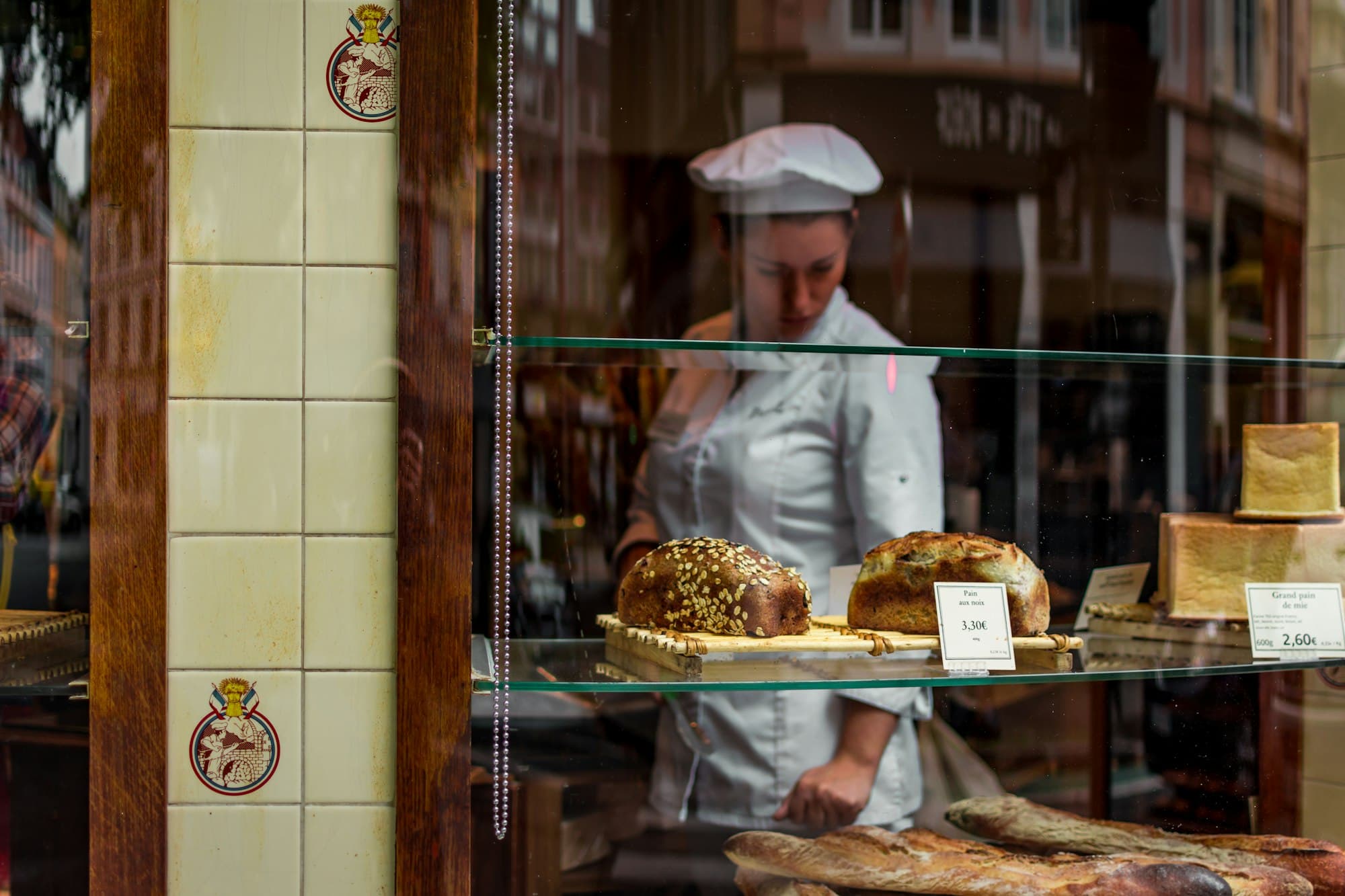 Loaves in a bakery window with the baker working behind