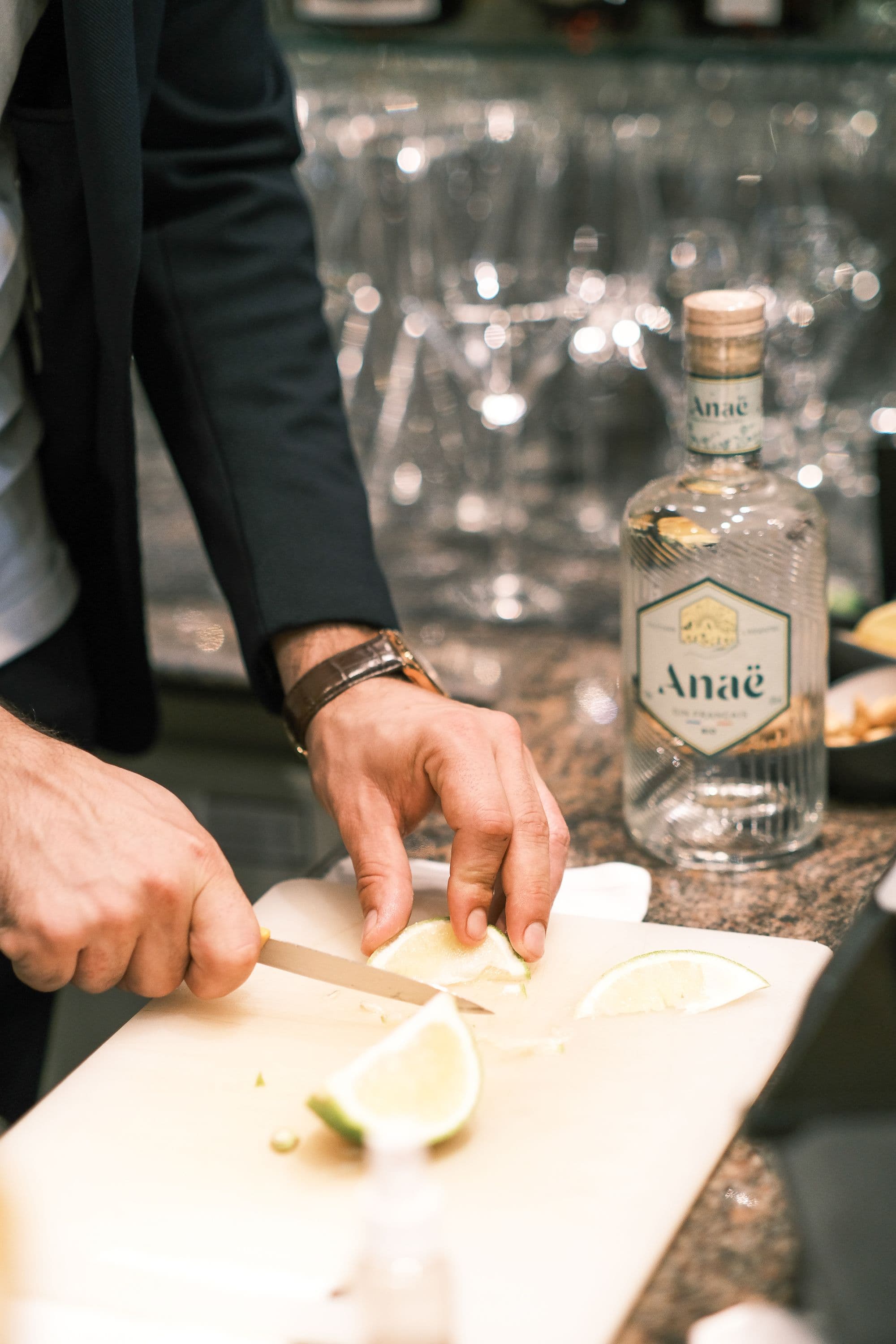 Hands slicing a lime on a board at a bar