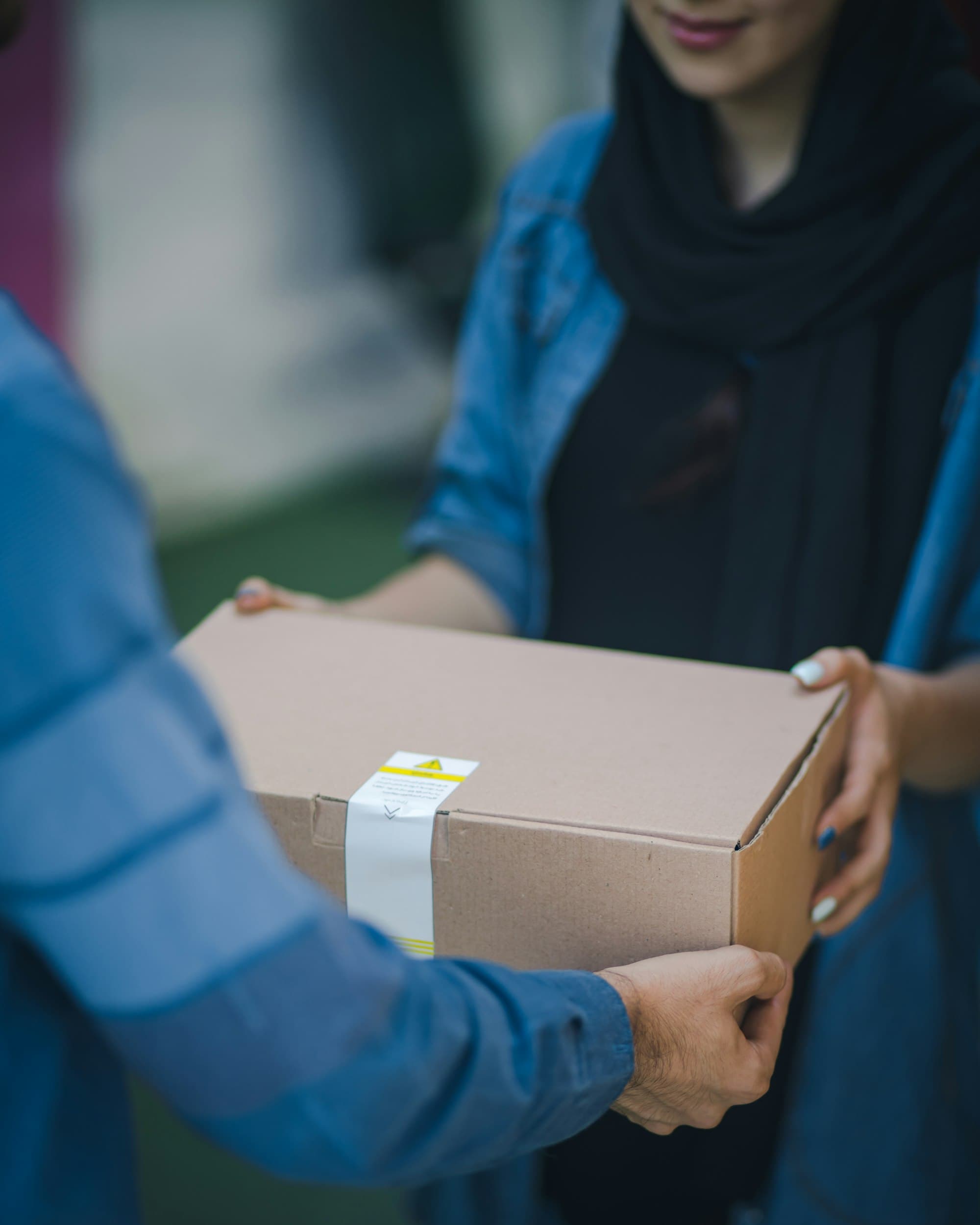 A cardboard box being handed from one person to another
